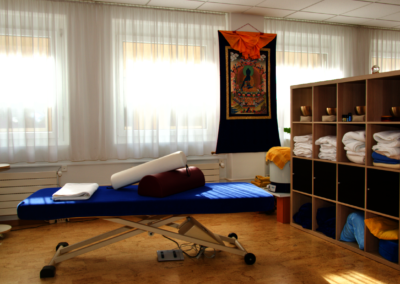 Behandlungsbereich des Praxisraums mit Therapieliege und Tücherregal